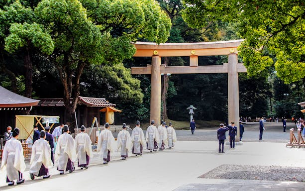 Priests walking under a torii gate at Meiji Jingu Shrine, Tokyo.