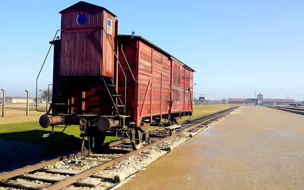 Railway car at Auschwitz-Birkenau with camp entrance in the background.