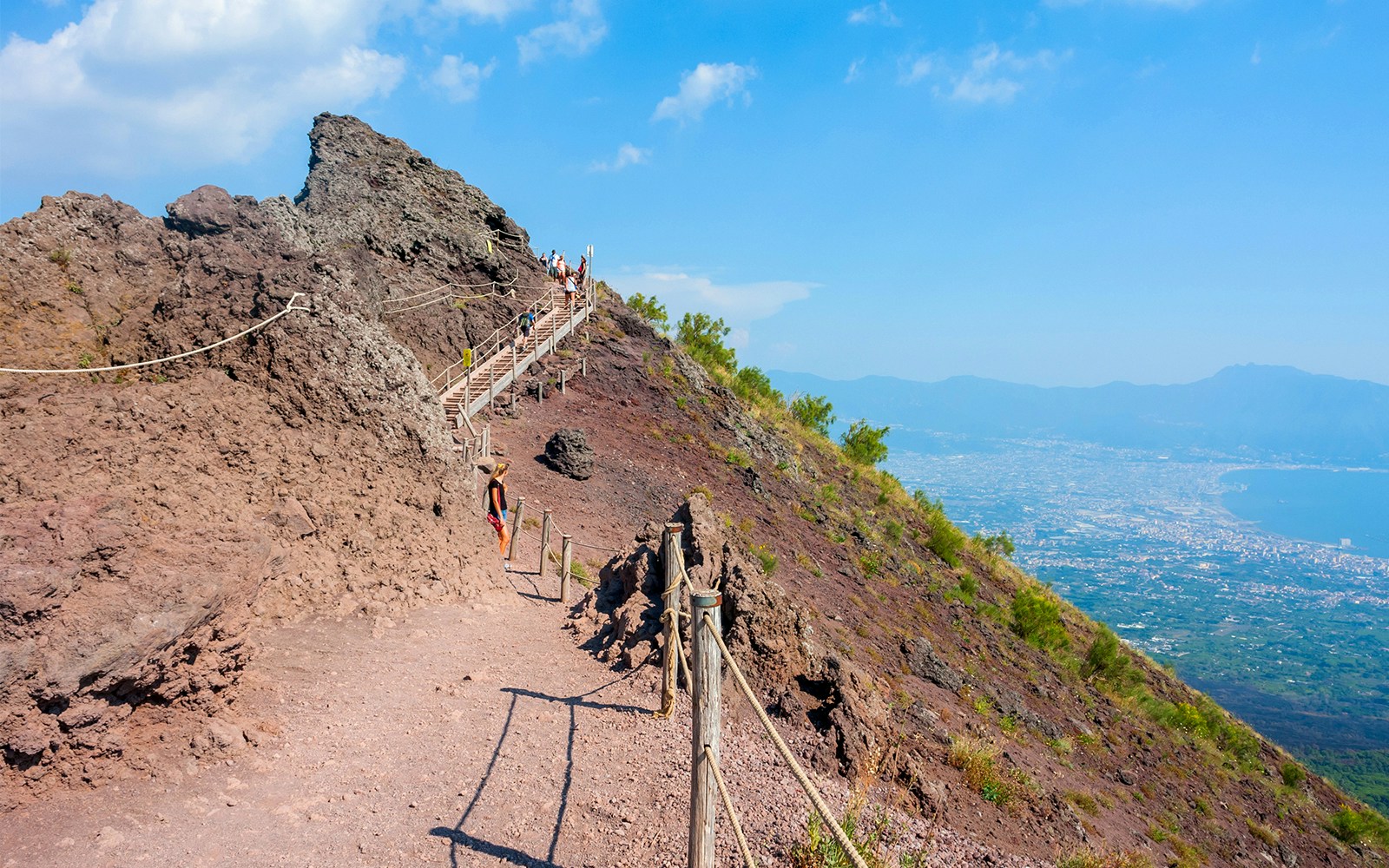 Hikers ascending Mount Vesuvius with panoramic views of Naples and the coastline.