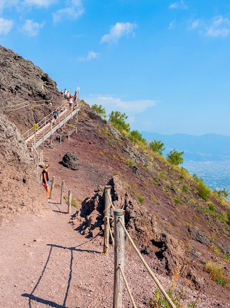 Hikers ascending Mount Vesuvius with panoramic views of Naples and the coastline.