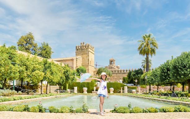 Visitor at the Gardens of the Alcazar de los Reyes Cristianos, Cordoba, Spain, near a fountain.