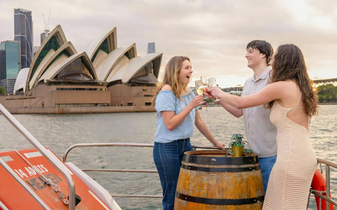 Friends toasting on a Sydney Harbour cruise with the Opera House in the background.