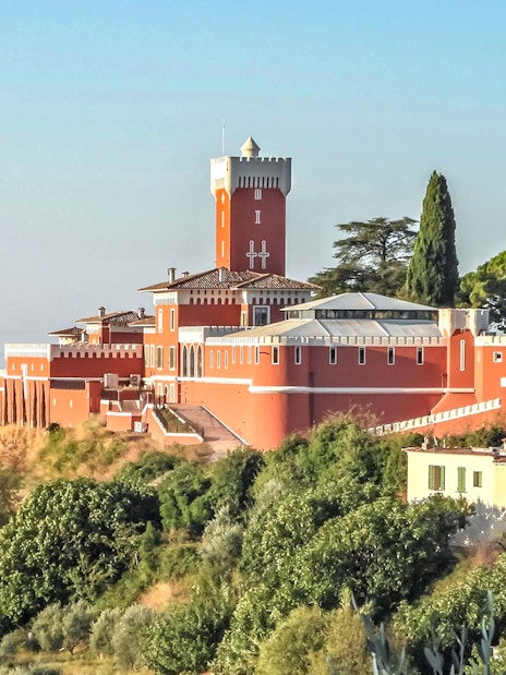 Provencal castle on a hill surrounded by greenery, part of a market and wine tasting tour.