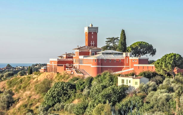 Provencal castle on a hill surrounded by greenery, part of a market and wine tasting tour.