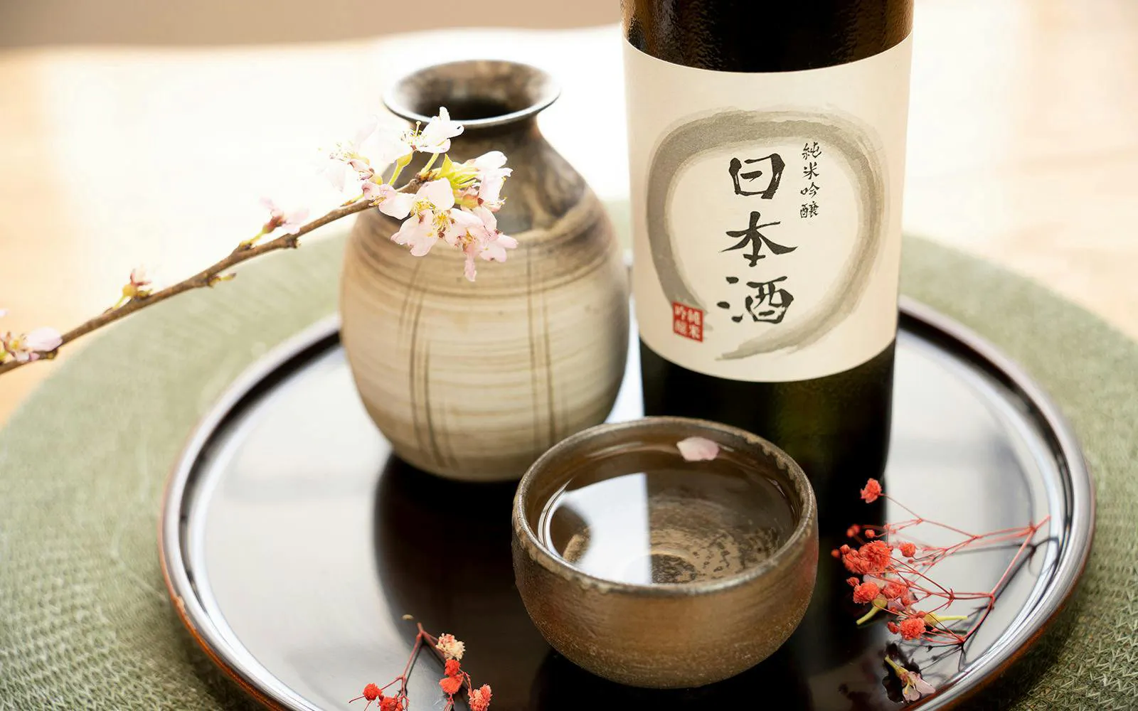 Sake bottle and cup with cherry blossoms at a tasting session.