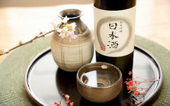 Sake bottle and cup with cherry blossoms at a tasting session.