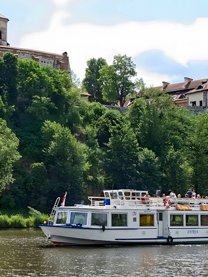 Sightseeing boat on Vistula River near historic monastery in Krakow, Poland.