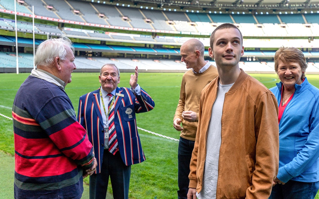 Tour group with guide at Melbourne Cricket Ground during sports walk.