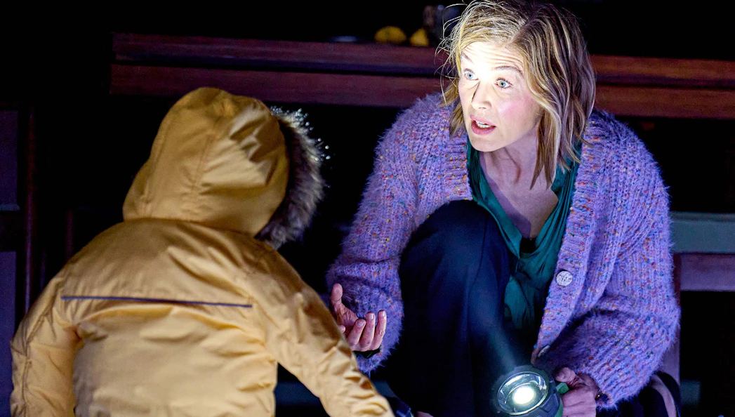 Broadway Inter Alia show scene with woman holding flashlight, engaging with child in yellow coat.