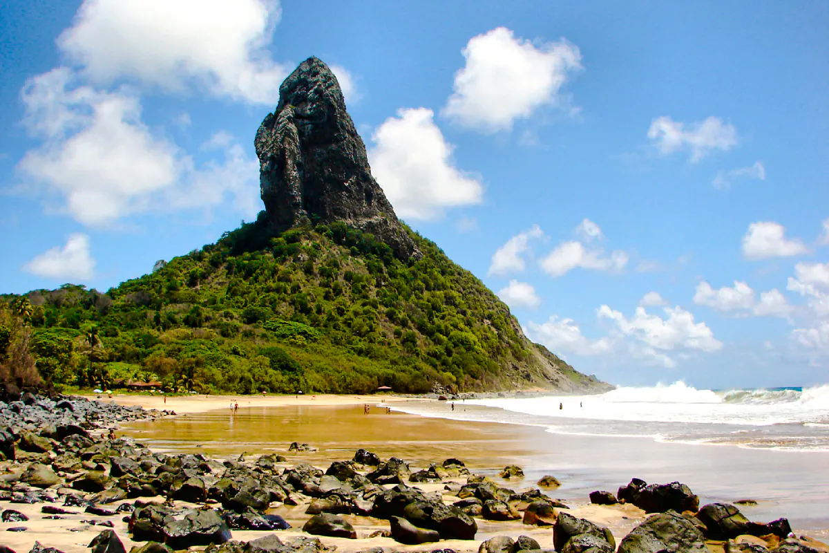 Fernando de Noronha beach with rocky shoreline and lush greenery, Brazil.