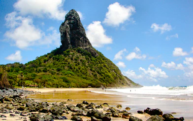 Fernando de Noronha beach with rocky shoreline and lush greenery, Brazil.