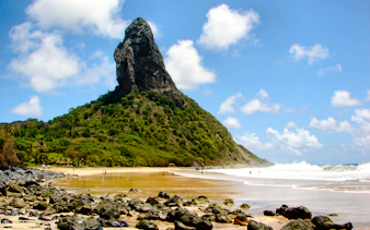 Fernando de Noronha beach with rocky shoreline and lush greenery, Brazil.