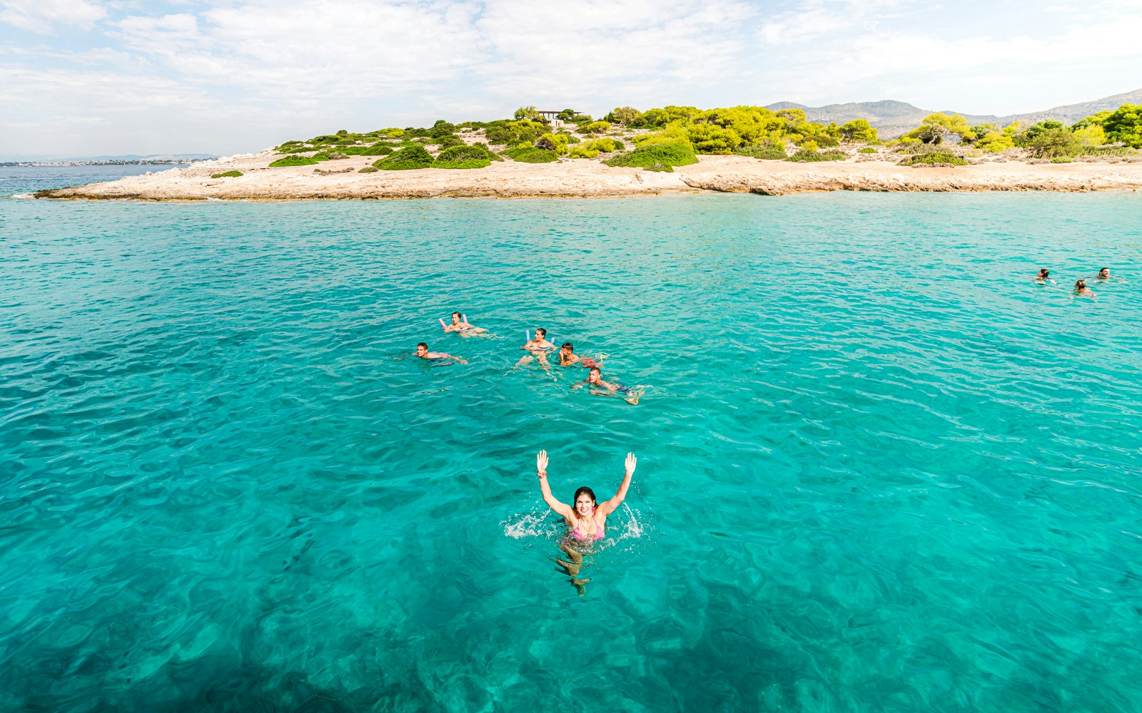 Group swimming in Saronic Gulf's turquoise waters during Athens sea adventure.