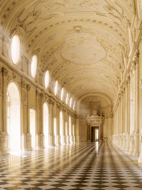 Grand hallway in Turin's Royal Palace with ornate ceiling and checkered floor.