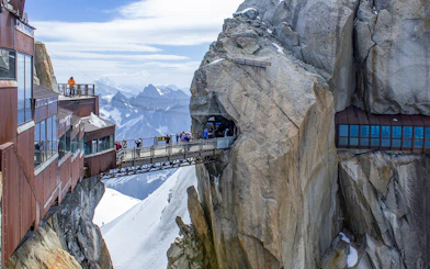 Tourists on a bridge at Aiguille du Midi, Chamonix, with Mont Blanc in the background.