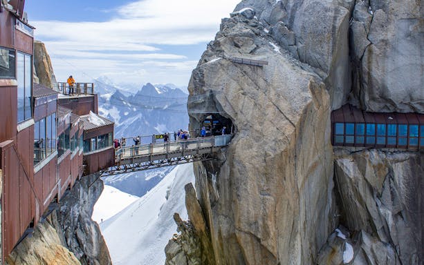 Tourists on a bridge at Aiguille du Midi, Chamonix, with Mont Blanc in the background.