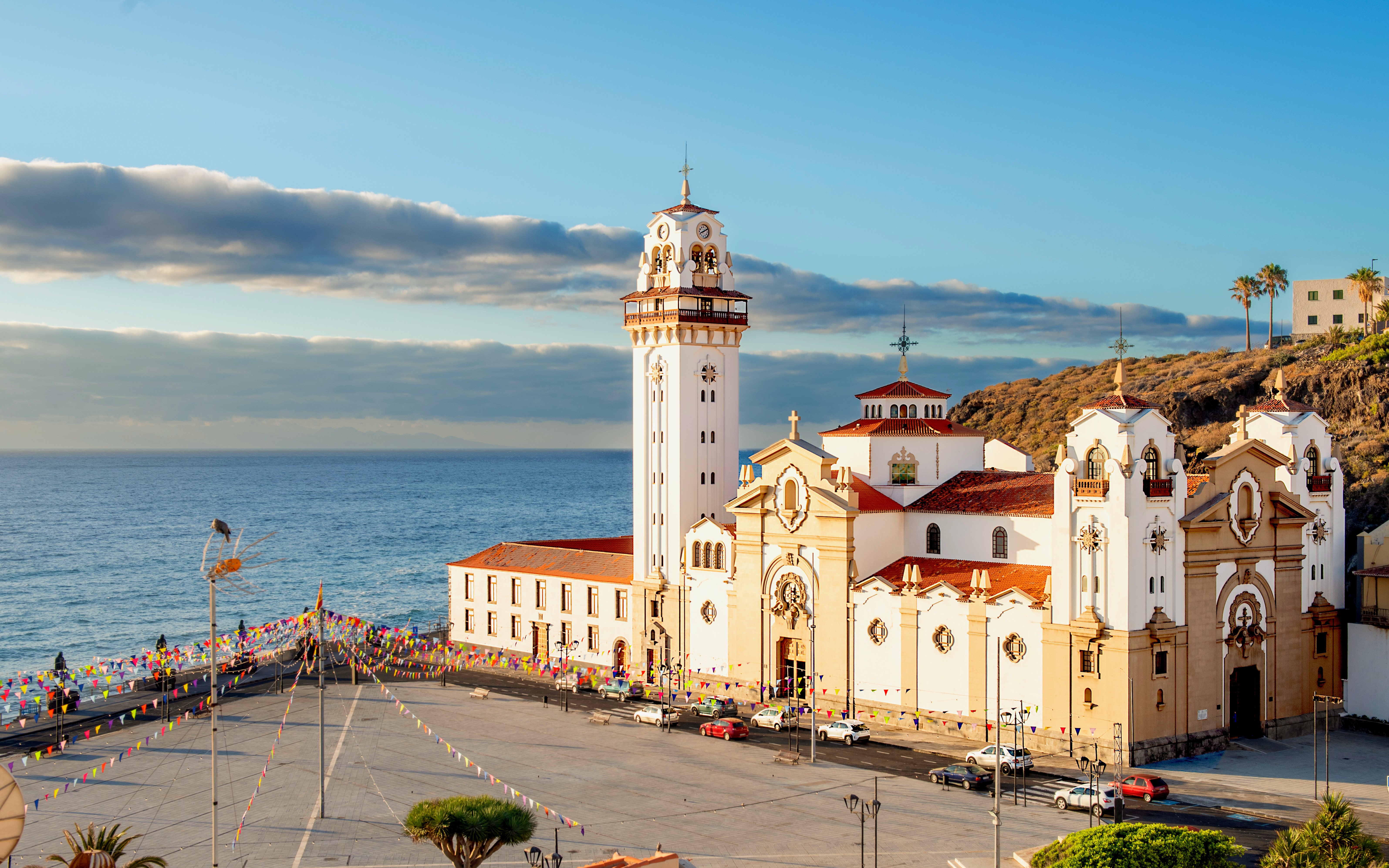 Basilica of Candelaria in Tenerife with ocean backdrop and festive flags.