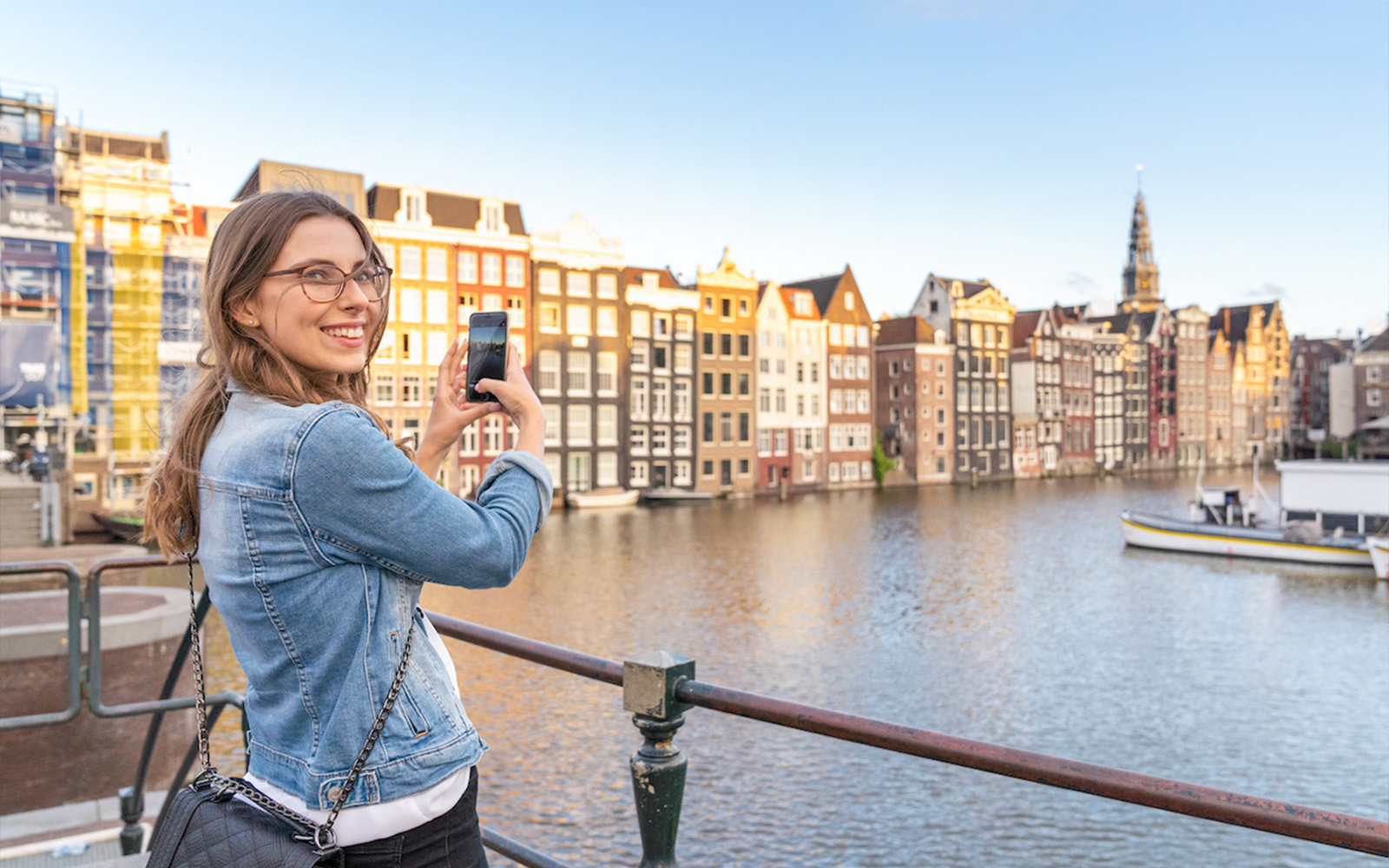 Tourist photographing canal houses in Amsterdam's red light district.