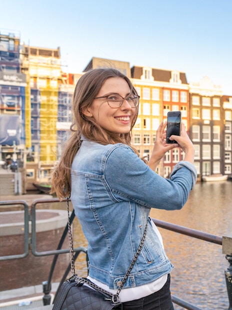 Tourist photographing canal houses in Amsterdam's red light district.