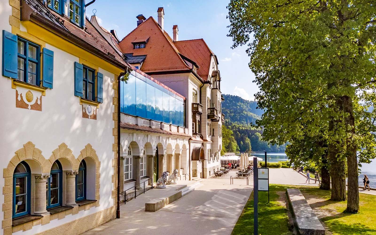Museum of the Bavarian Kings building with outdoor seating and lake view.