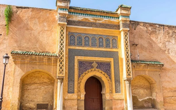 Historic gate in Meknes, Morocco with intricate tilework and archway.