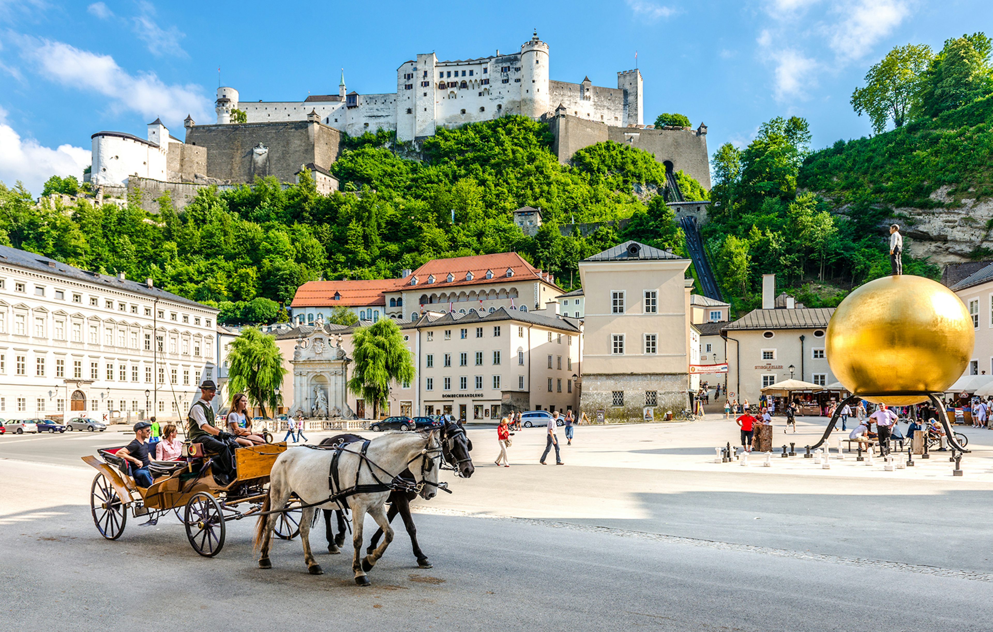 Horse-drawn carriage in Salzburg's old town with Hohensalzburg Fortress, Austria.