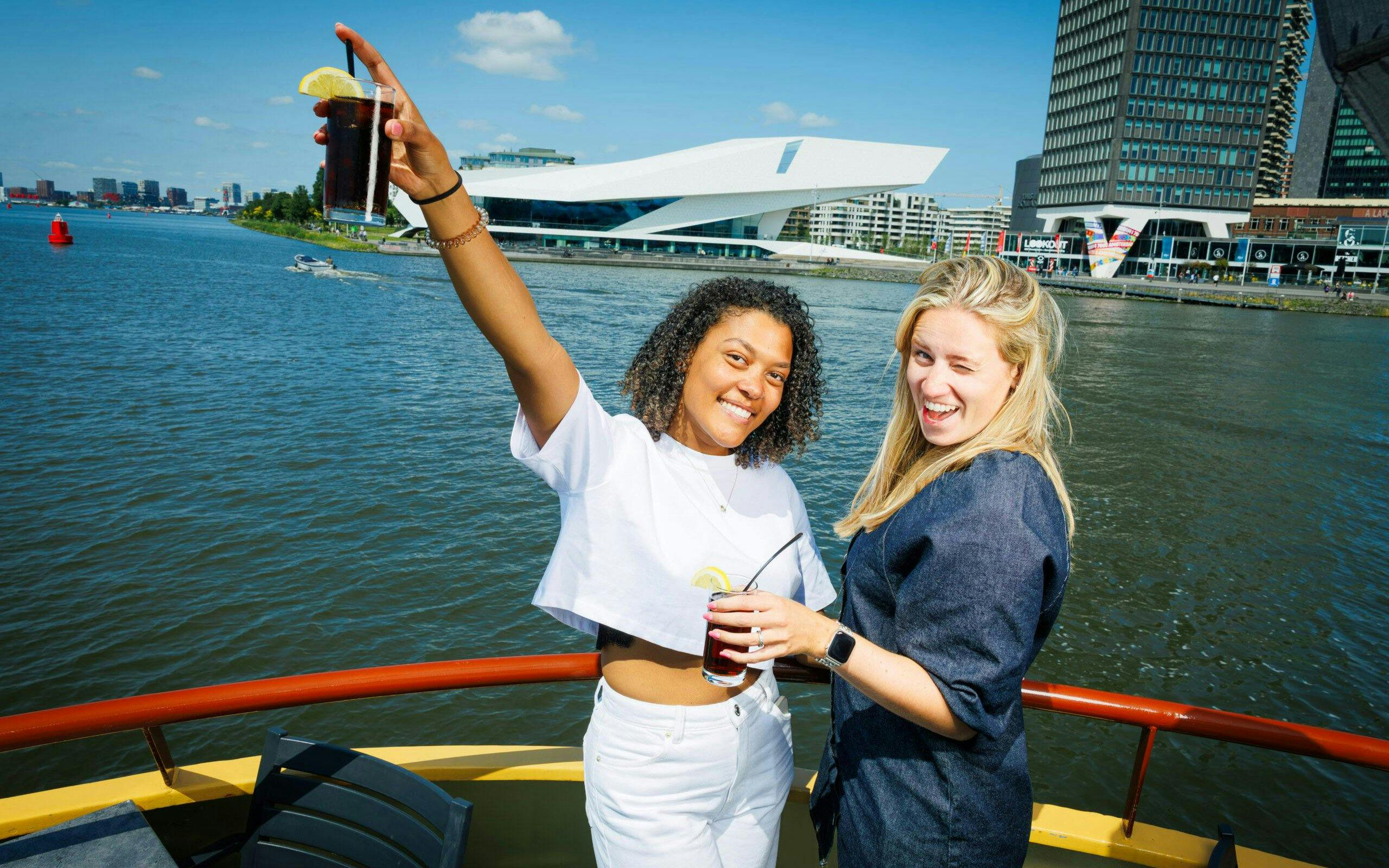 Guests enjoying drinks on a Dutch Pancake cruise in Amsterdam with cityscape views.