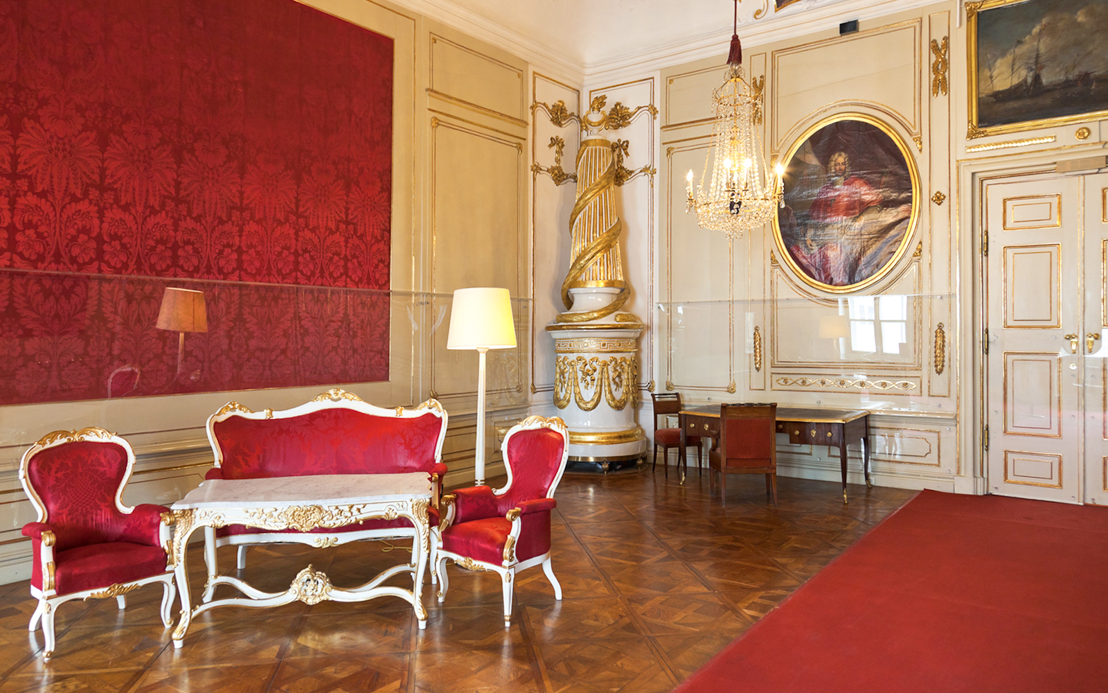 Imperial Apartments Sisi Museum interior with ornate red furniture and chandelier.