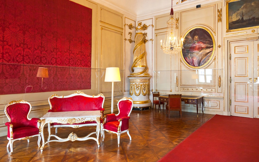 Imperial Apartments Sisi Museum interior with ornate red furniture and chandelier.