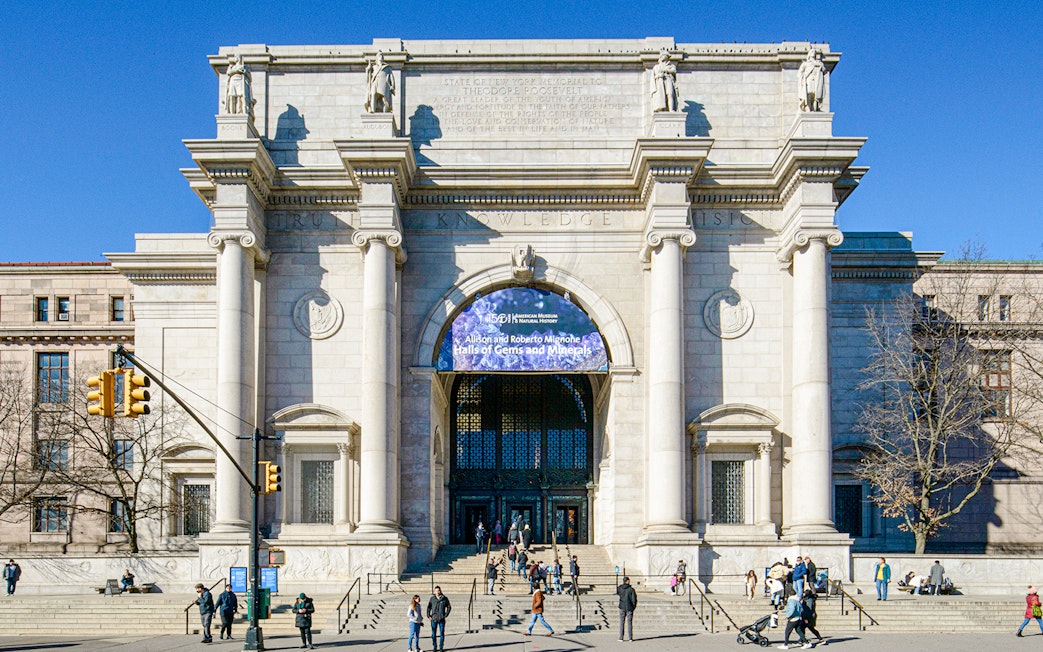 American Museum of Natural History entrance in New York City with visitors outside.