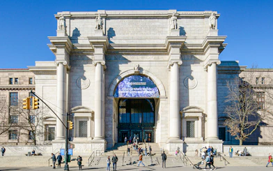 American Museum of Natural History entrance in New York City with visitors outside.