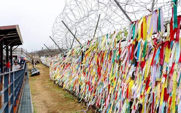 Colorful ribbons on barbed wire fence at Korean Demilitarized Zone during private day tour.