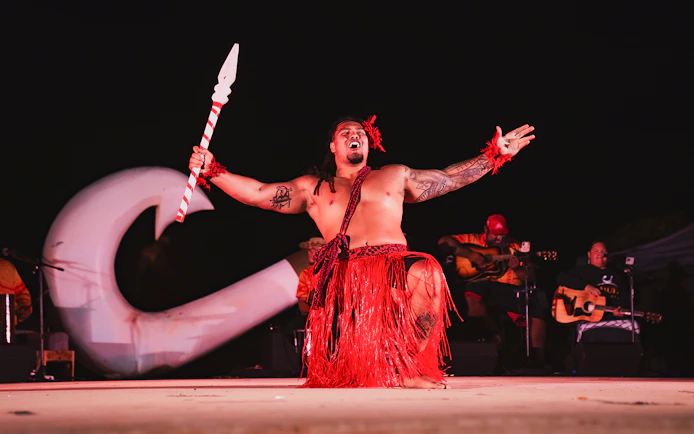 Mauka Warrior performing traditional dance on stage at a Luau.