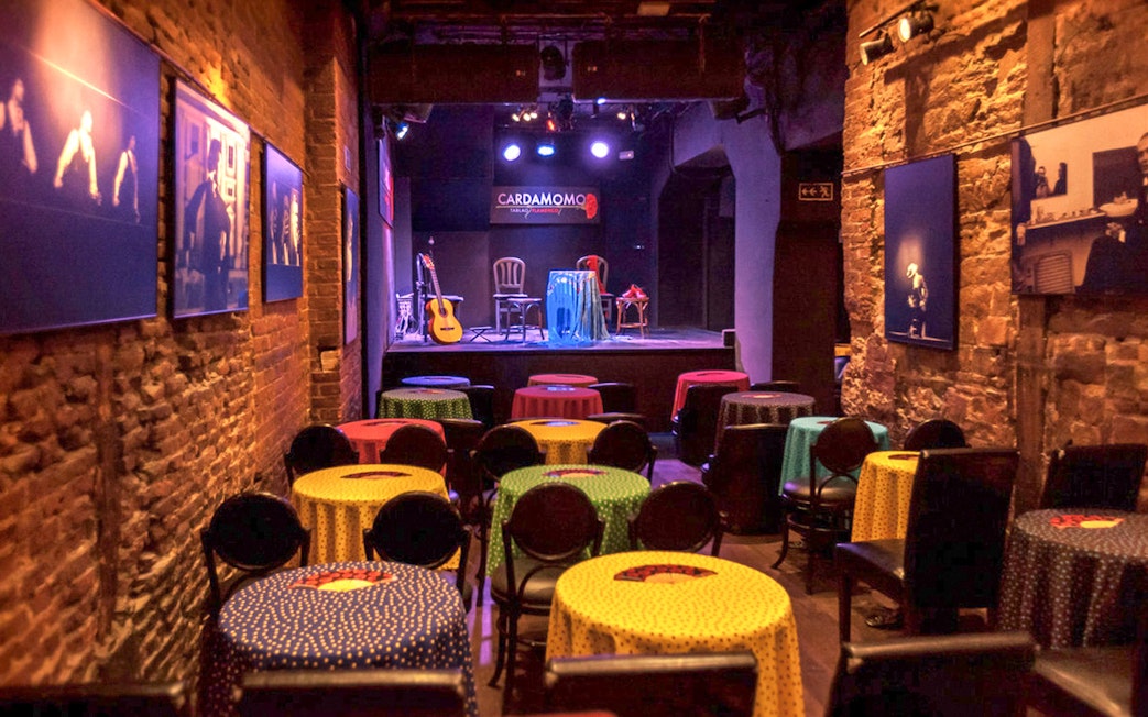 Tablao Cardamomo stage with colorful tables and flamenco guitar in Madrid.