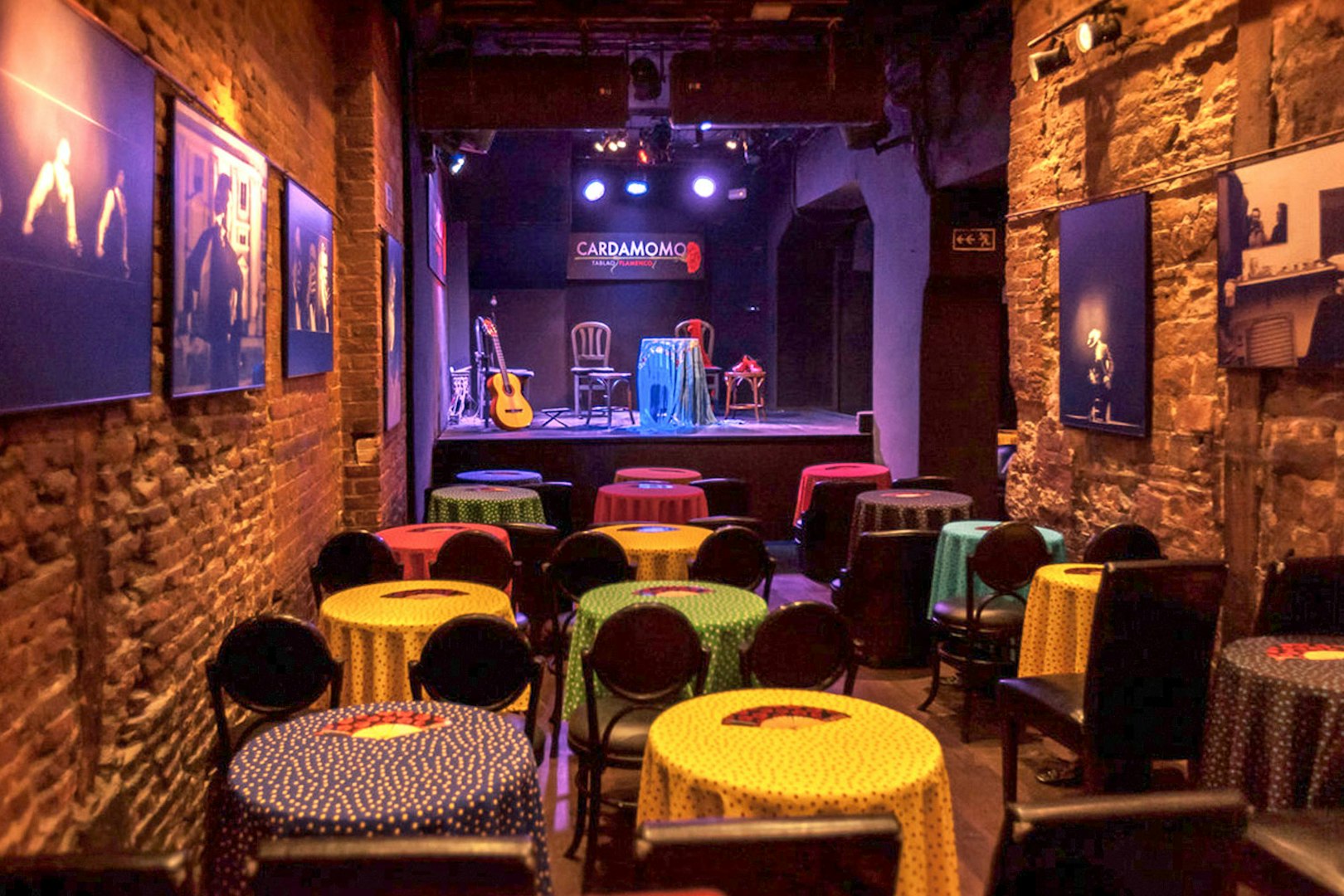 Tablao Cardamomo stage with colorful tables and flamenco guitar in Madrid.