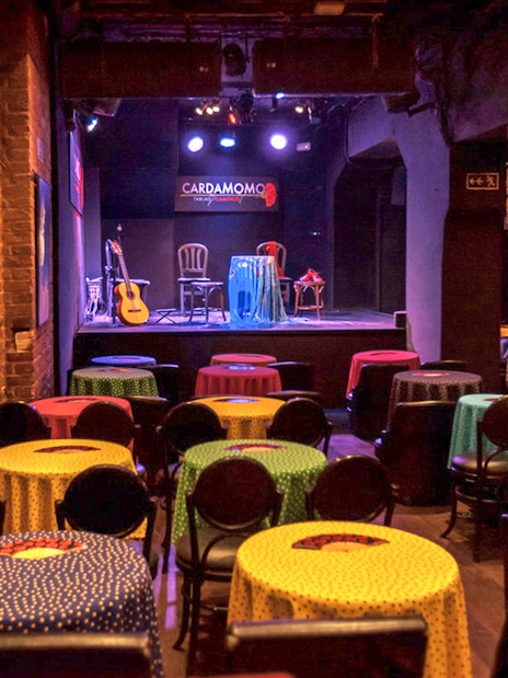 Tablao Cardamomo stage with colorful tables and flamenco guitar in Madrid.