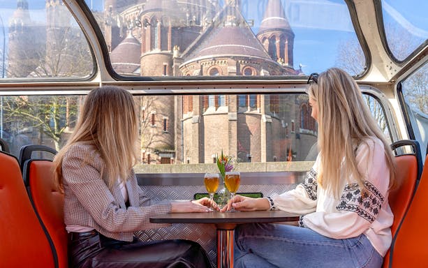 Two people enjoying drinks on a canal cruise in Haarlem with a historic building view.