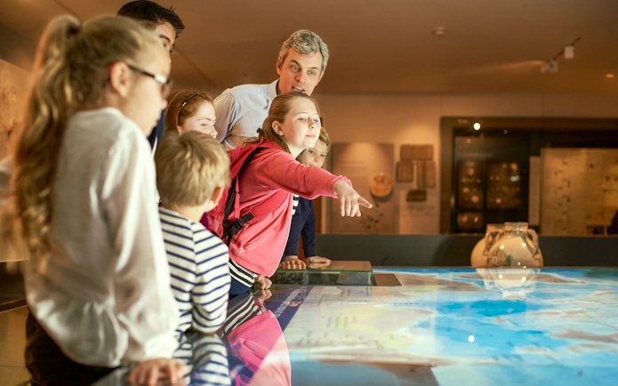 Children engaged in an interactive museum exhibit during a guided tour.