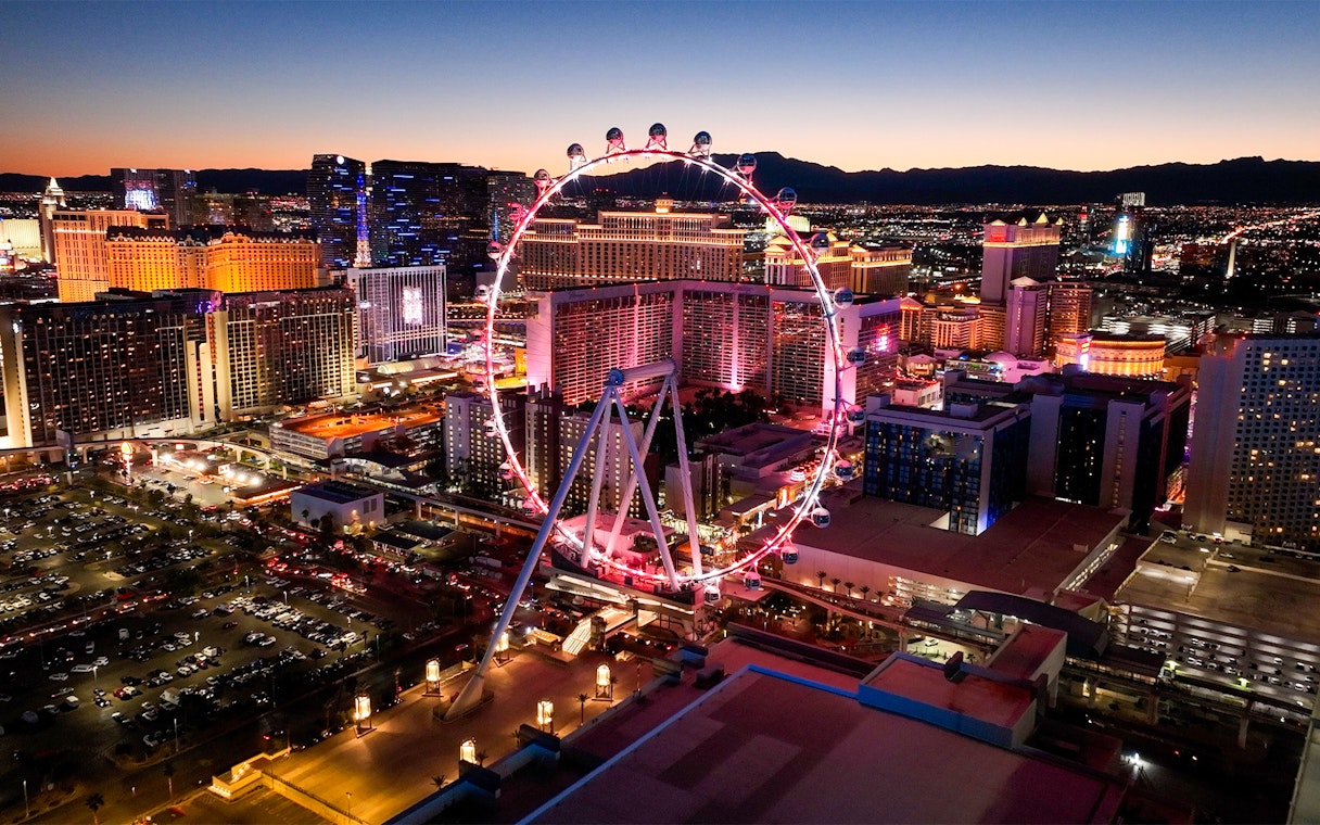 High Roller observation wheel illuminated at night, Las Vegas skyline in background.