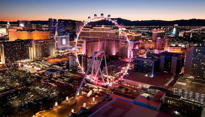 High Roller observation wheel illuminated at night, Las Vegas skyline in background.