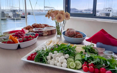 Breakfast spread on catamaran cruise from Gdansk with fruits, pastries, and cheese.