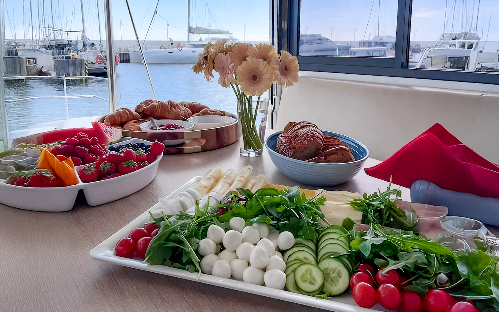 Breakfast spread on catamaran cruise from Gdansk with fruits, pastries, and cheese.
