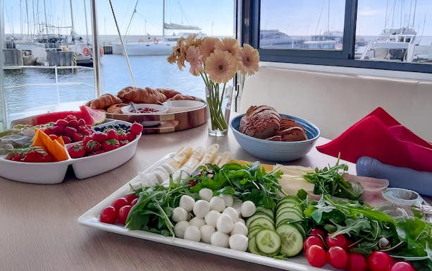 Breakfast spread on catamaran cruise from Gdansk with fruits, pastries, and cheese.