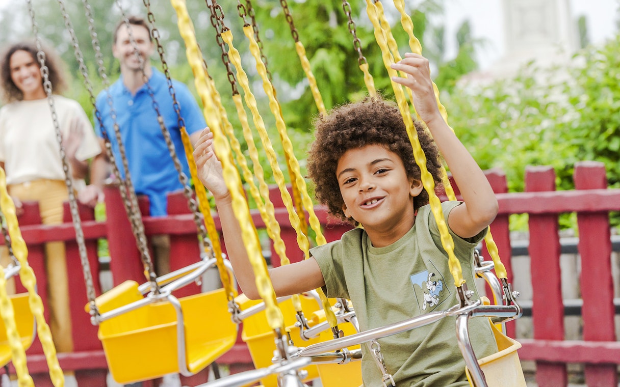 Child enjoying a swing ride at Parc Asterix, France.
