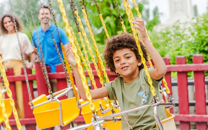 Child enjoying a swing ride at Parc Asterix, France.