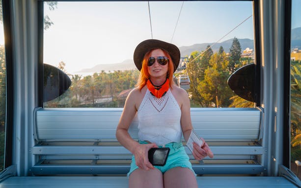 Person enjoying a cable car ride in Alanya with scenic views of trees and mountains.