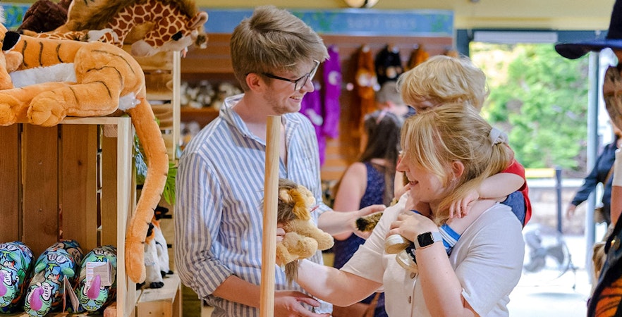 Family browsing plush toys at Edinburgh Zoo gift shop.