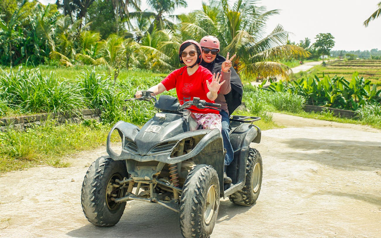 ATV riders on a dirt path in Ubud, surrounded by lush greenery.