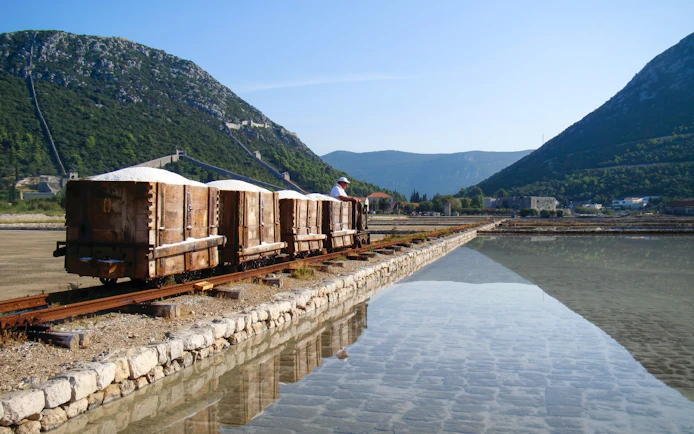 Small train transporting salt at Ston salt pans, Croatia, with mountains in the background.