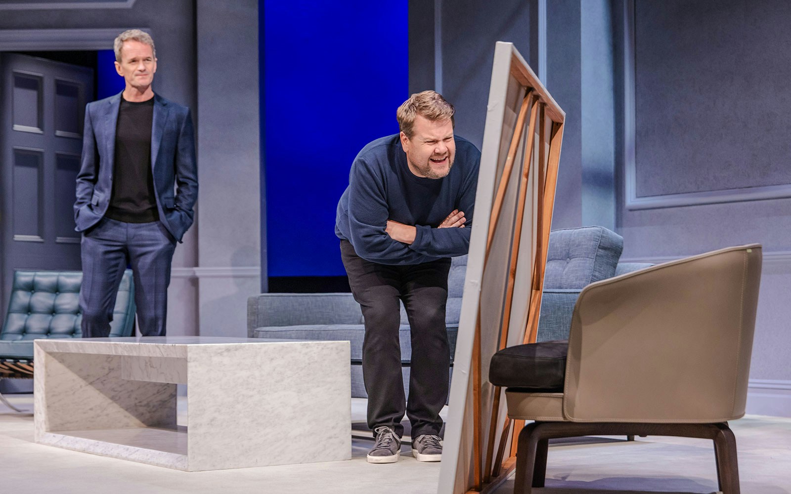 Two actors performing a scene from the Art Broadway show on stage.